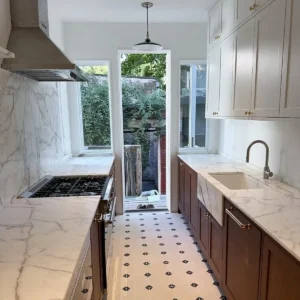 Custom galley kitchen renovation featuring marble countertops, white upper cabinets, dark wood lower cabinets, and modern finishes.