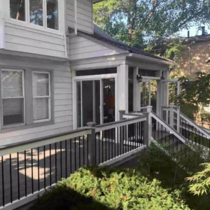 Custom sunroom addition with sliding glass doors, composite deck, and notice, modern railing system.
